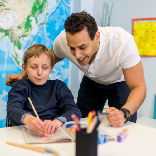 Educatore che supporta un ragazzo che vive una disabilità nellos tudio
